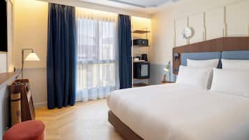 Une chambre d’hôtel avec un grand lit, un bureau avec une lampe, une télévision et une machine à café.
