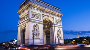 A large, ornate historical monument with intricate carvings and a prominent archway, surrounded by a busy street with moving vehicles. - Urban Hive Paris (Paris)