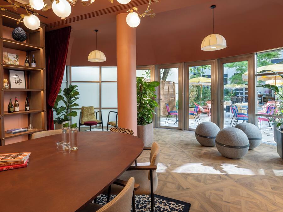 A dining area with a wooden table, chairs, and a bookshelf with books and decorative items.