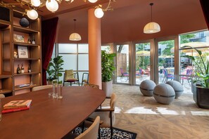 Un coin repas avec une table en bois, des chaises et une bibliothèque contenant des livres et des objets décoratifs.