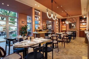A restaurant with multiple dining tables and chairs, large windows, and a variety of lighting fixtures.