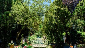 A garden with a white bridge, potted plants, and a table with a white tablecloth. - Luxury Vintage Hotel Villa Beukenhof (Oegstgeest)