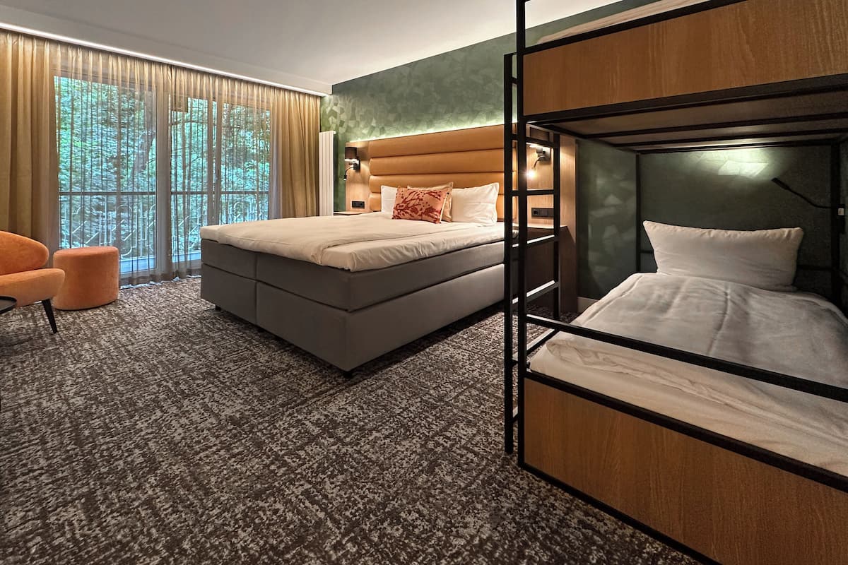 Habitación de hotel con una cama grande, una cama más pequeña, un sofá y una silla.