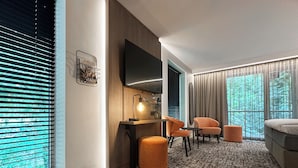 Una sala moderna con un sofá, dos sillones, una mesa de centro y un televisor montado en la pared.