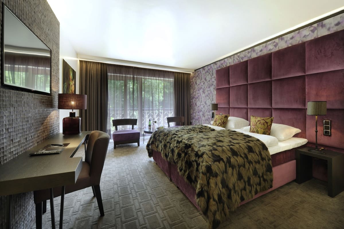 Una habitación de hotel moderna con una cama grande, un escritorio y una zona de estar.