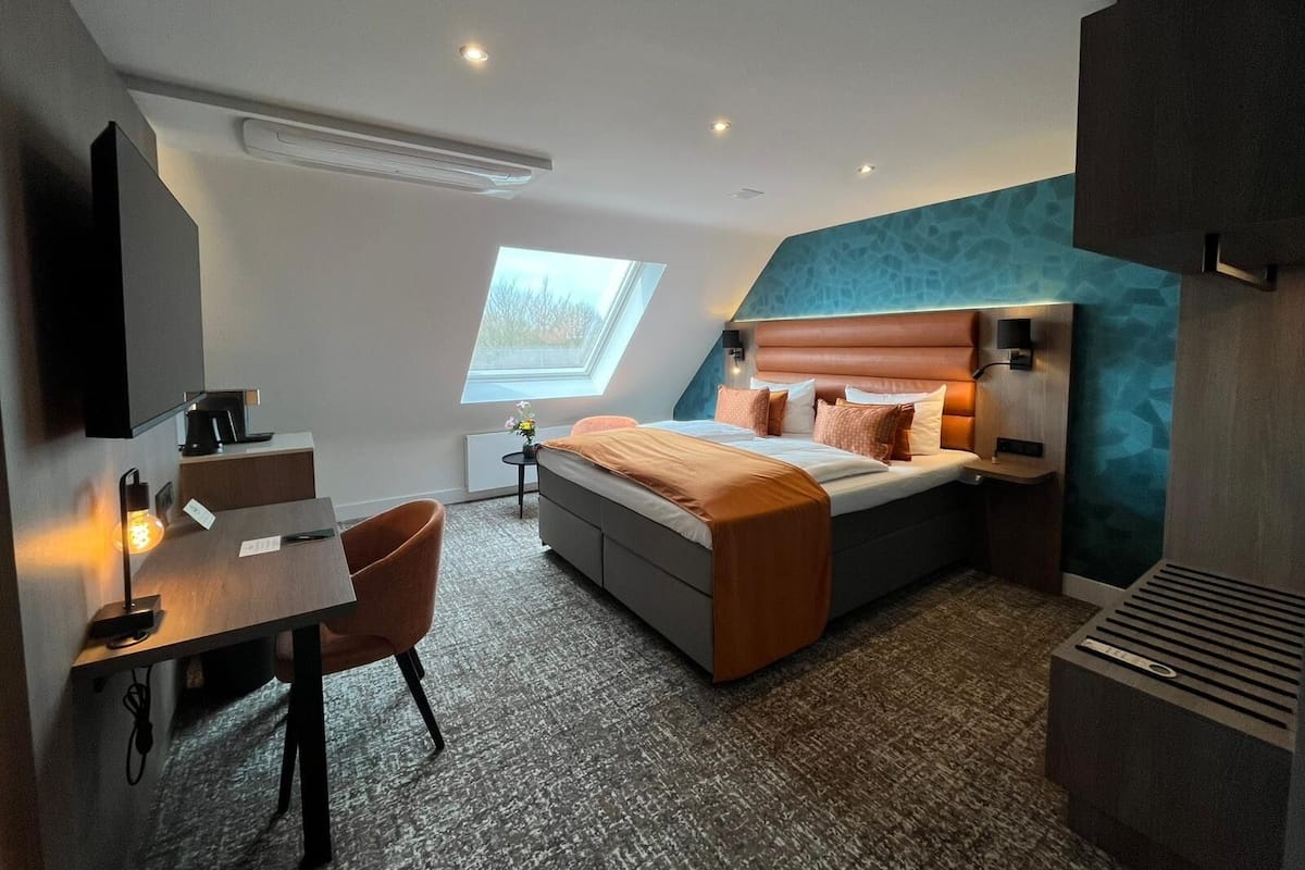 Una habitación de hotel moderna con cama, escritorio, silla y tragaluz.