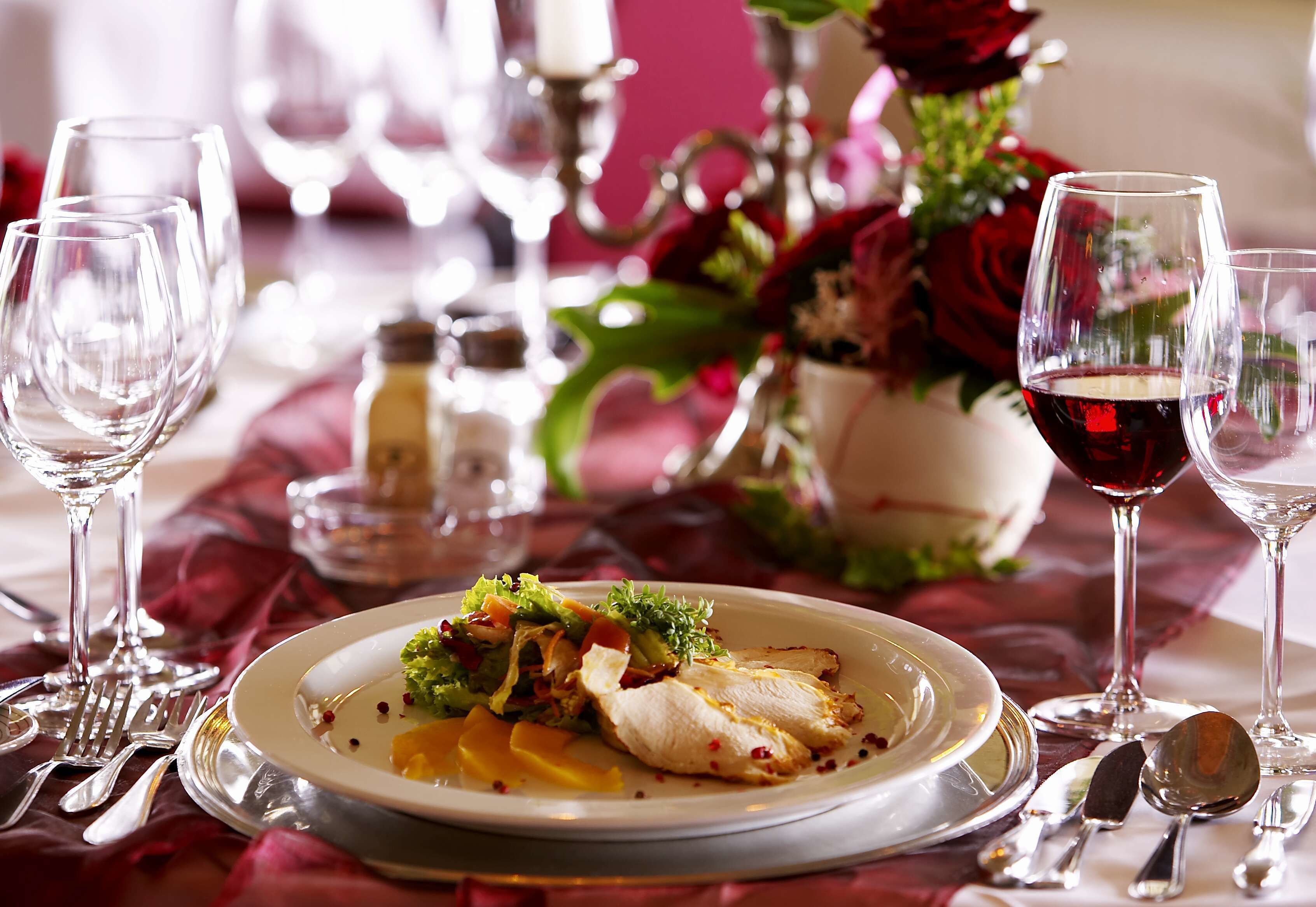 Une table à manger dressée avec une assiette de nourriture, des verres à vin et des couverts.