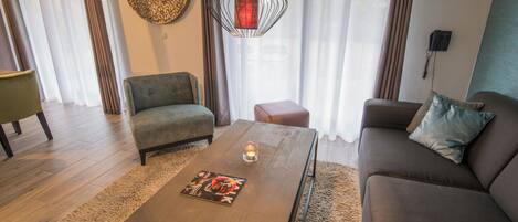 A living room with a sofa, armchair, coffee table, and a hanging light fixture.