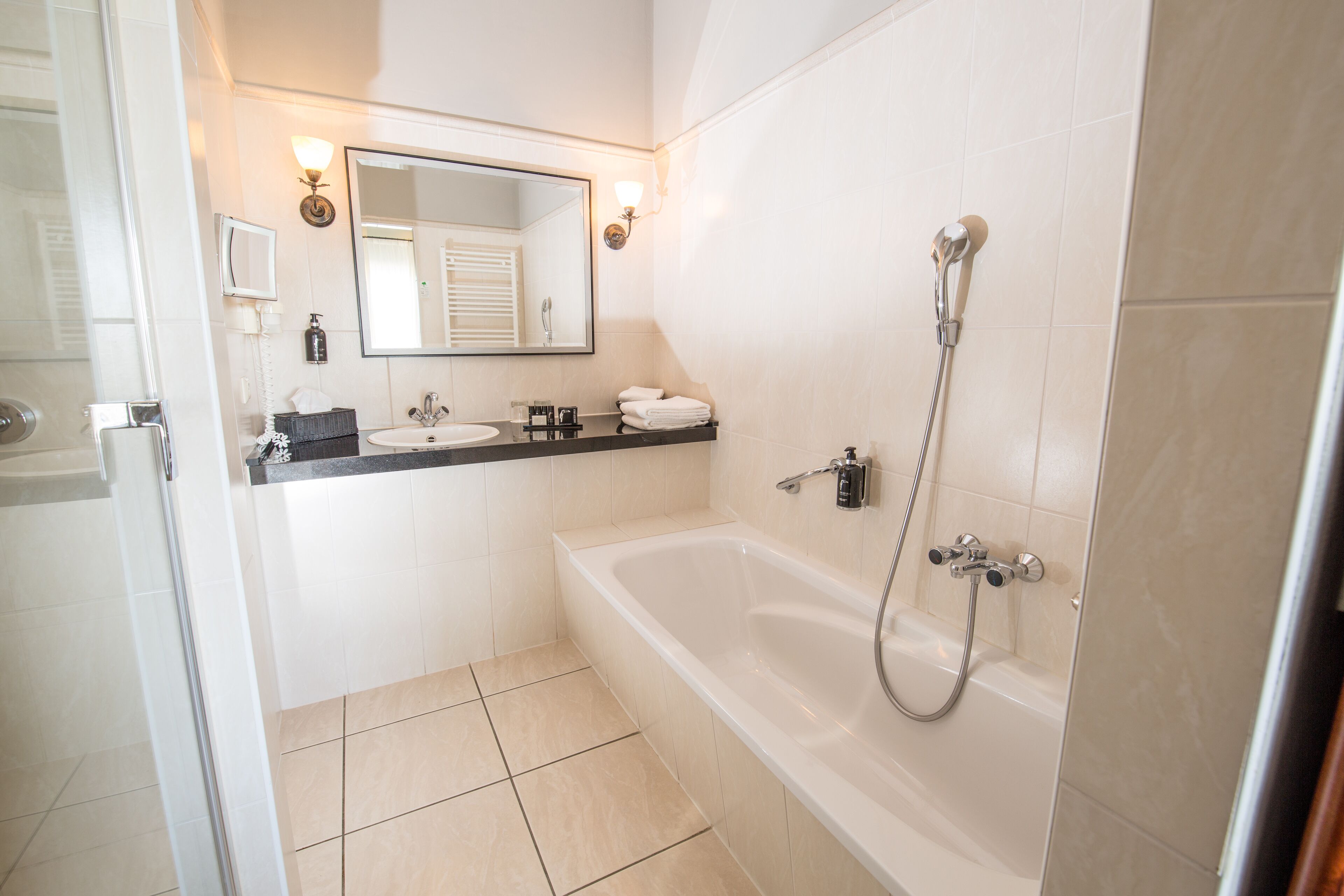 Un baño moderno con bañera, dos lavamanos, un espejo y ducha.