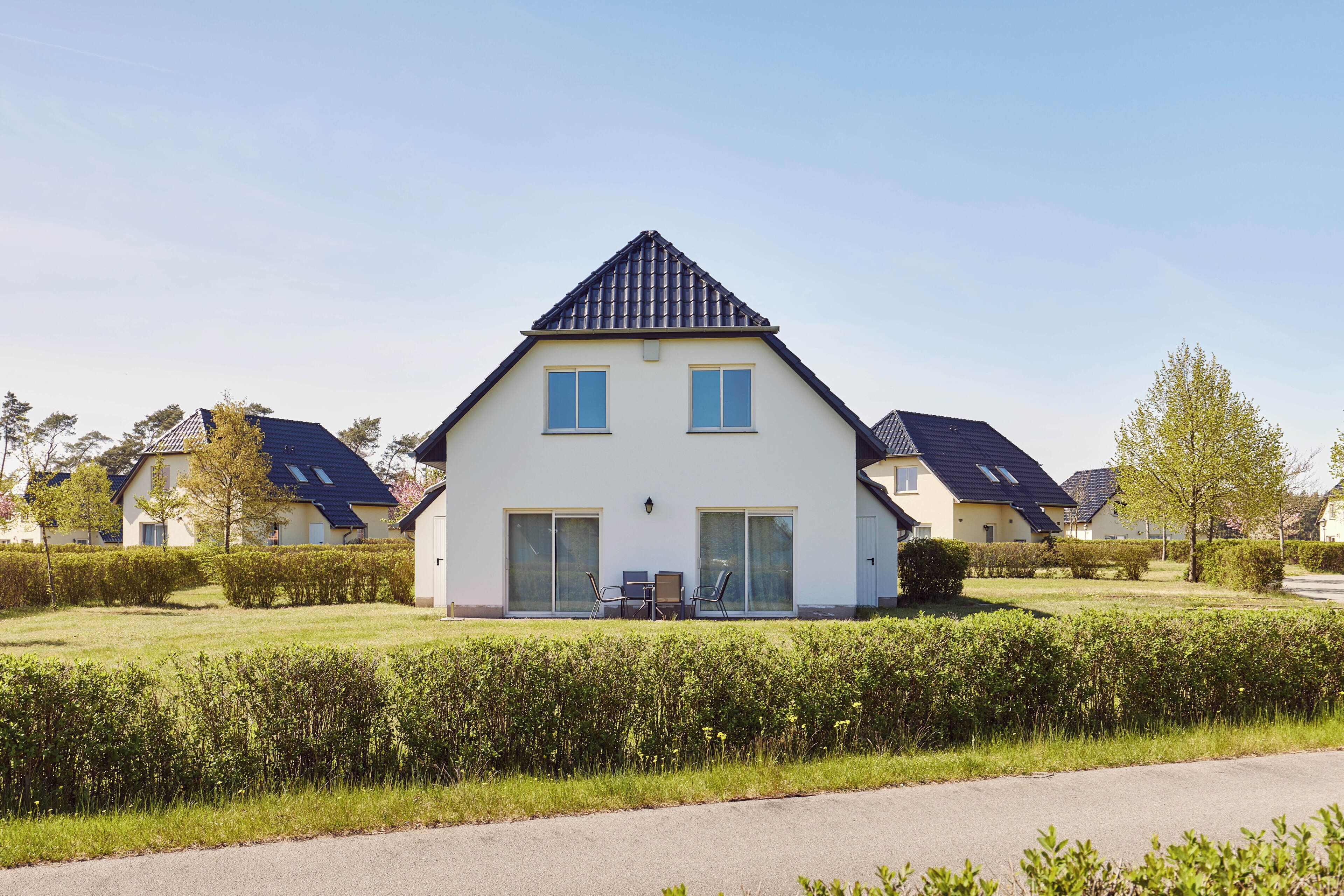 Ein modernes, zweistöckiges Haus mit geneigtem Dach, großen Fenstern und einem gepflegten Rasen.
