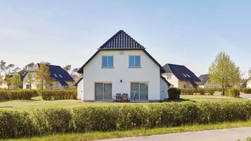 Ein modernes, zweistöckiges Haus mit geneigtem Dach, großen Fenstern und einem gepflegten Rasen.