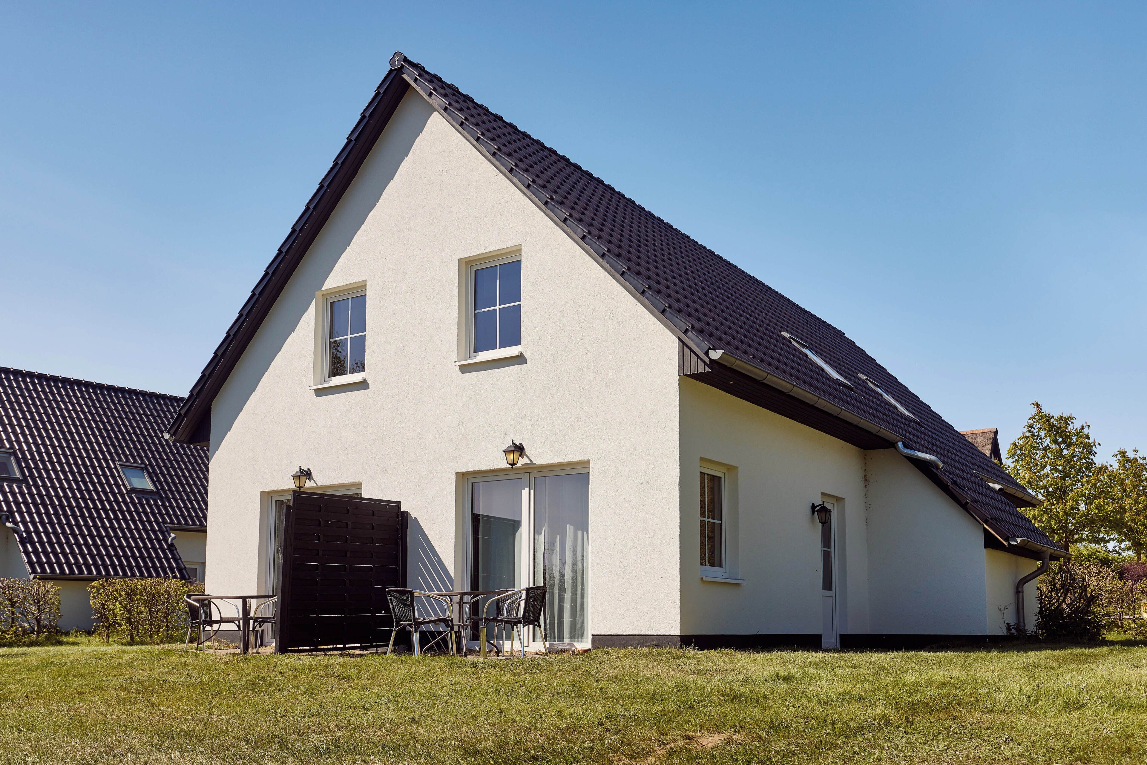 A two-story house with a dark roof, a front door, and a small window.