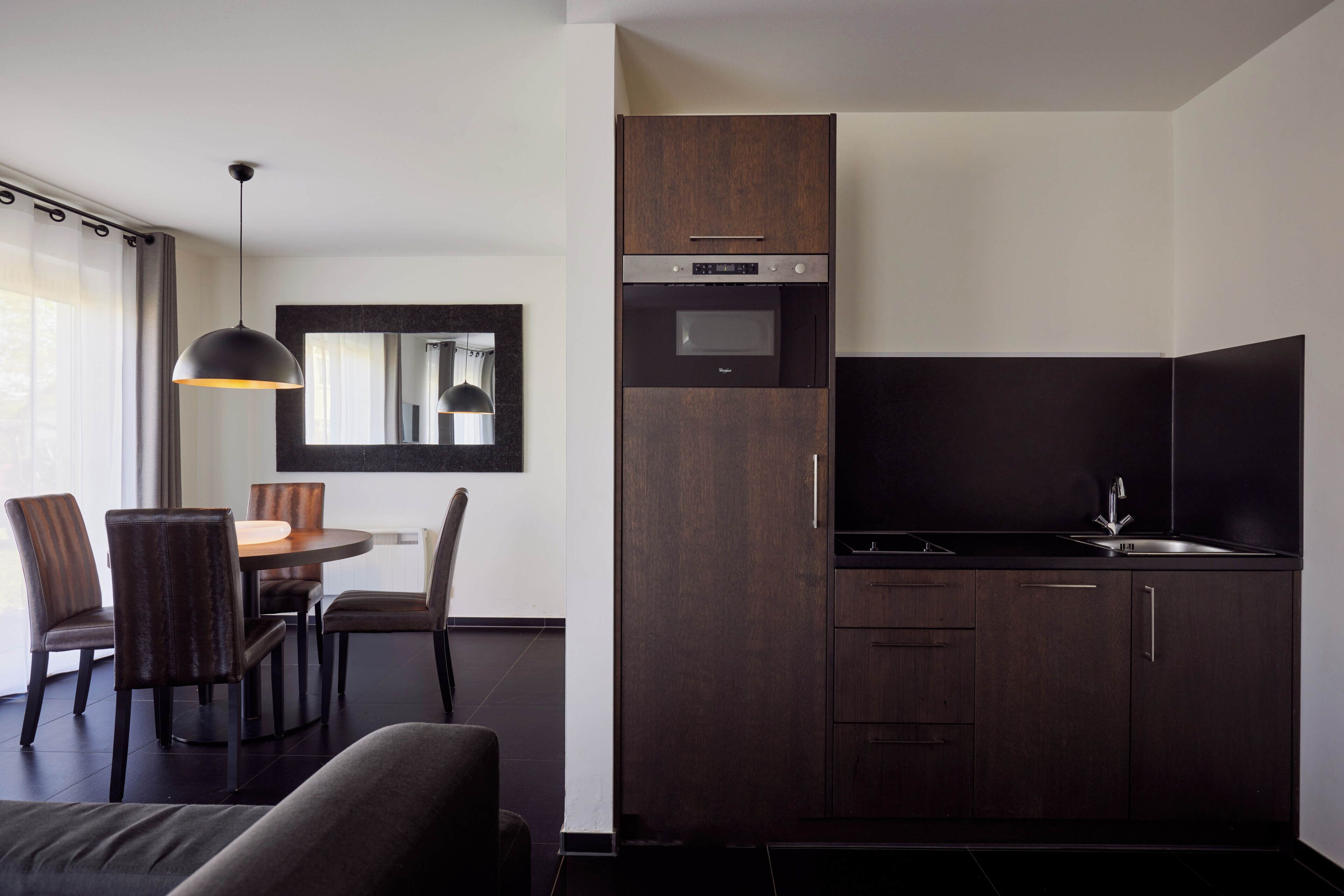 A modern kitchen with dark wood cabinets, a built-in oven, and a sink.