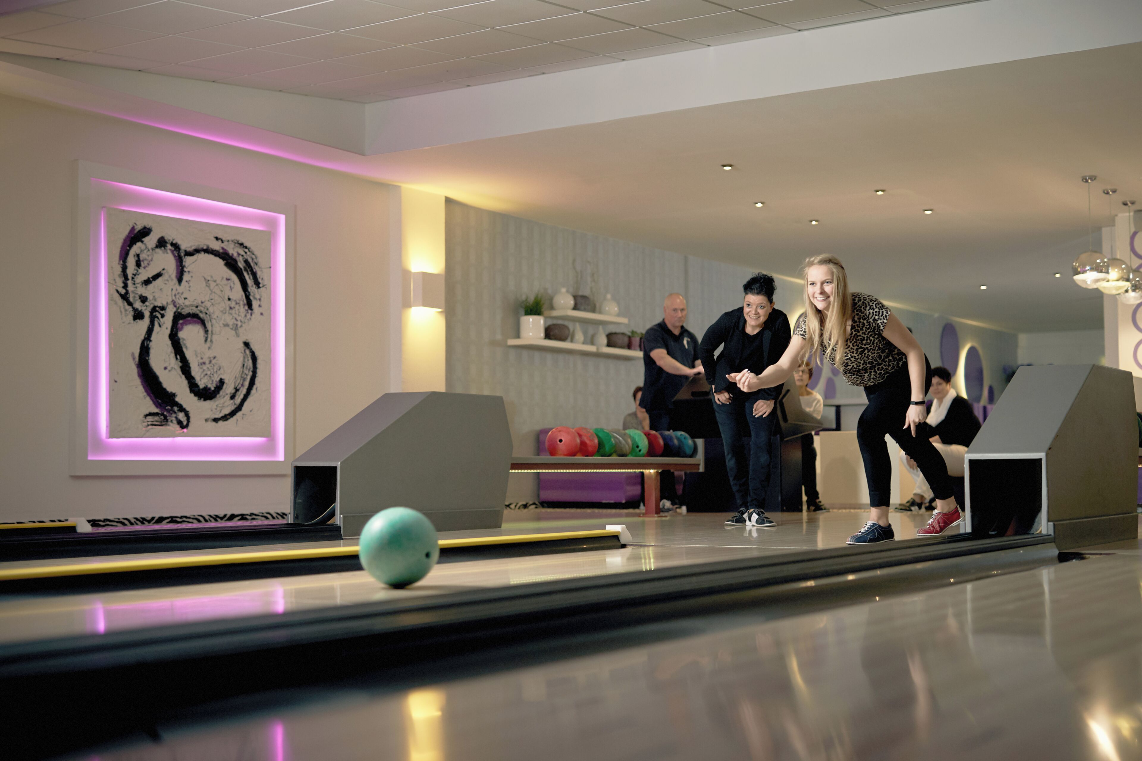 Un bowling au design moderne, avec une œuvre d’art illuminée par des néons et un sol impeccable et bien entretenu.