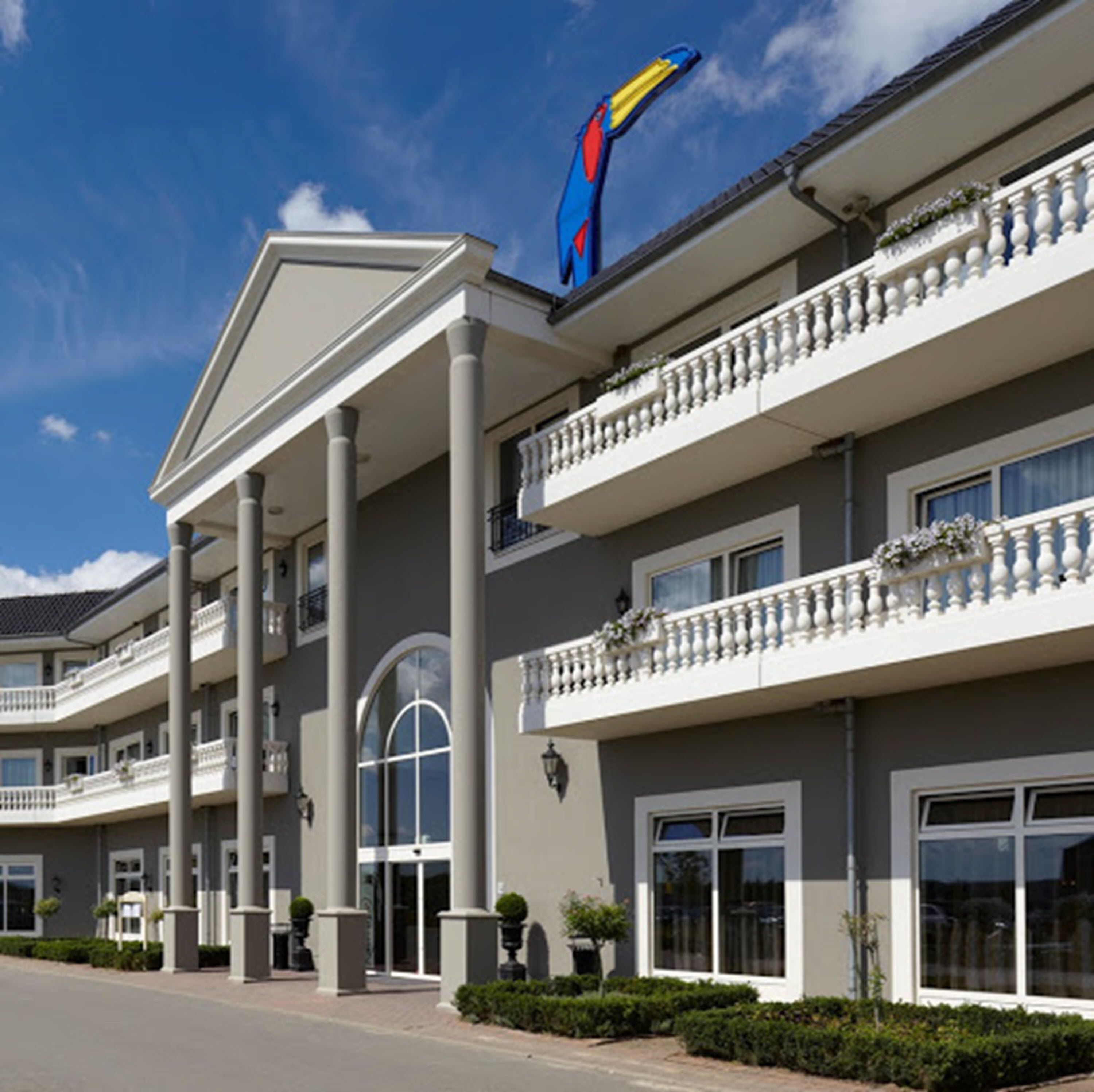 A multi-story hotel with a prominent blue and yellow sign, large columns, and balconies with railings.