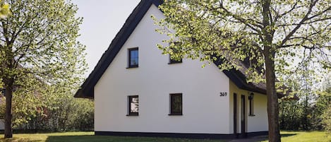 A white building with a black roof, numbered 369, surrounded by trees and grass.