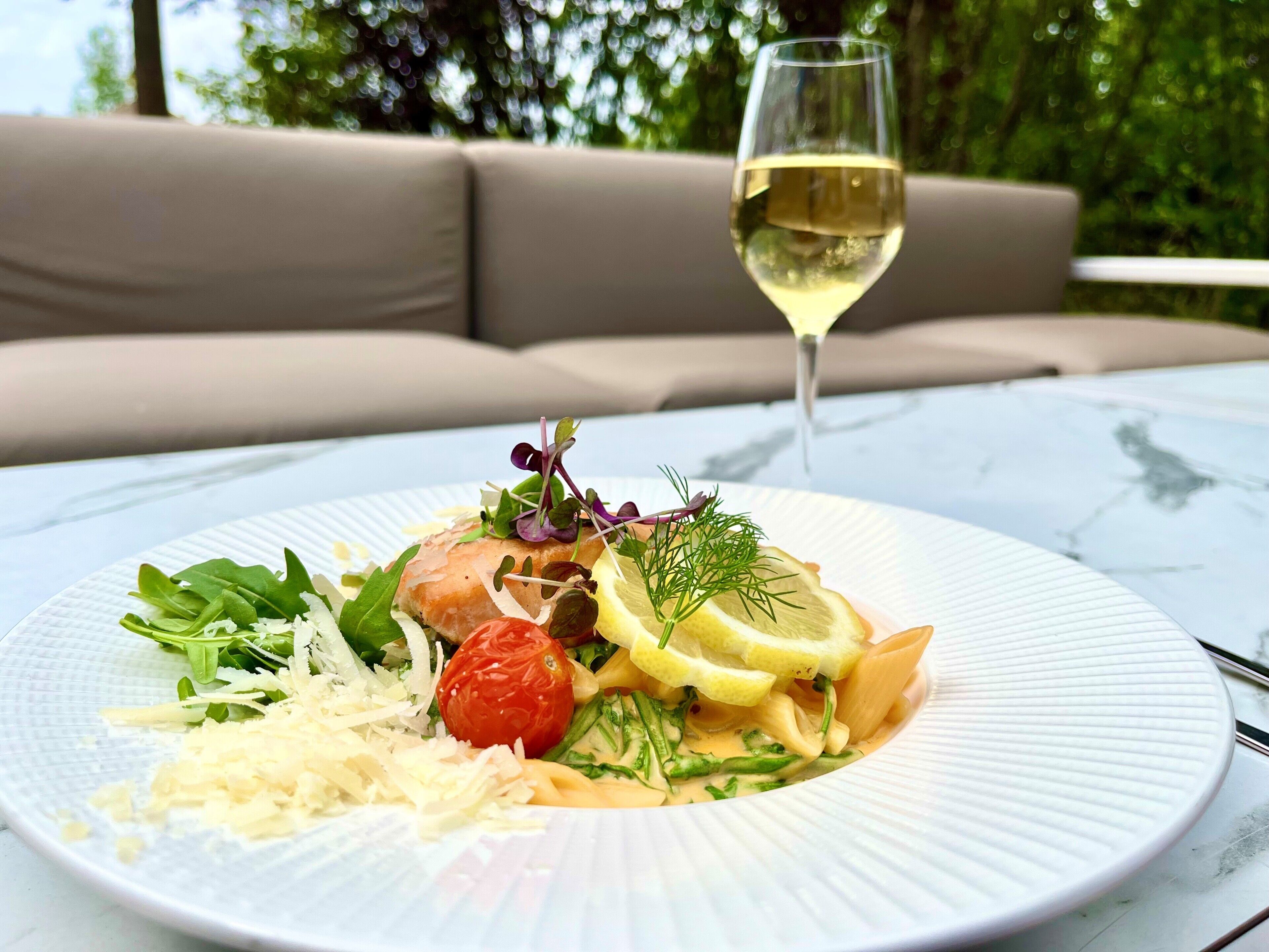 Une assiette de nourriture et un verre de vin blanc sur une table.