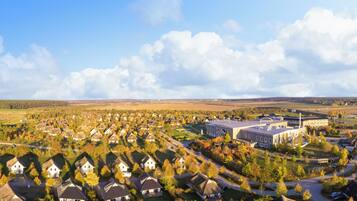 An aerial view of a residential area with houses, a large building, and open fields.