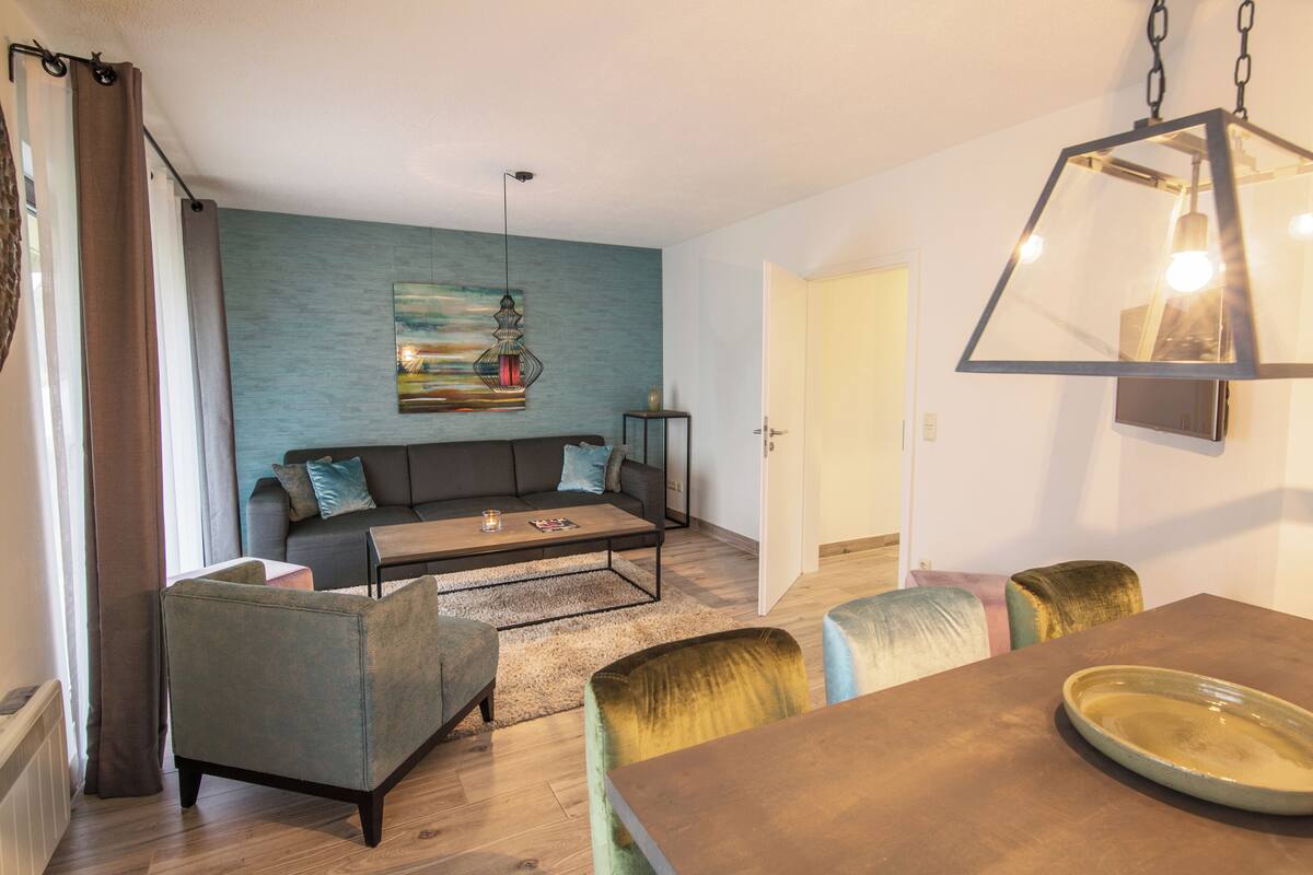 A living room with a sofa, coffee table, chairs, and a dining table.