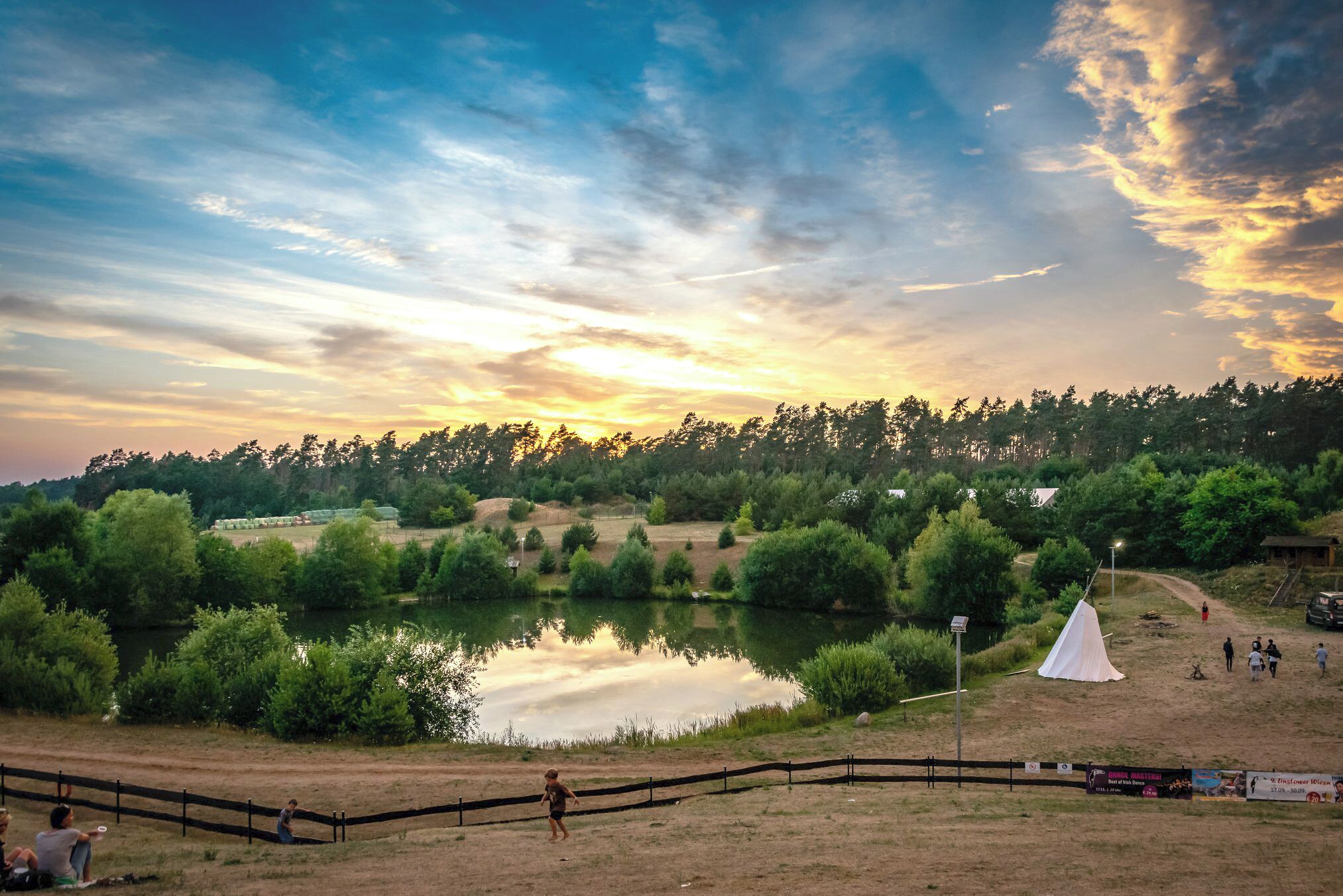 Un campamento con una tienda de campaña, un lago y un sendero de tierra.