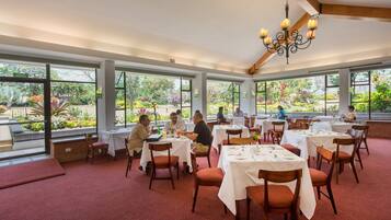 Un ristorante con ampie vetrate, tavoli e sedie in legno.