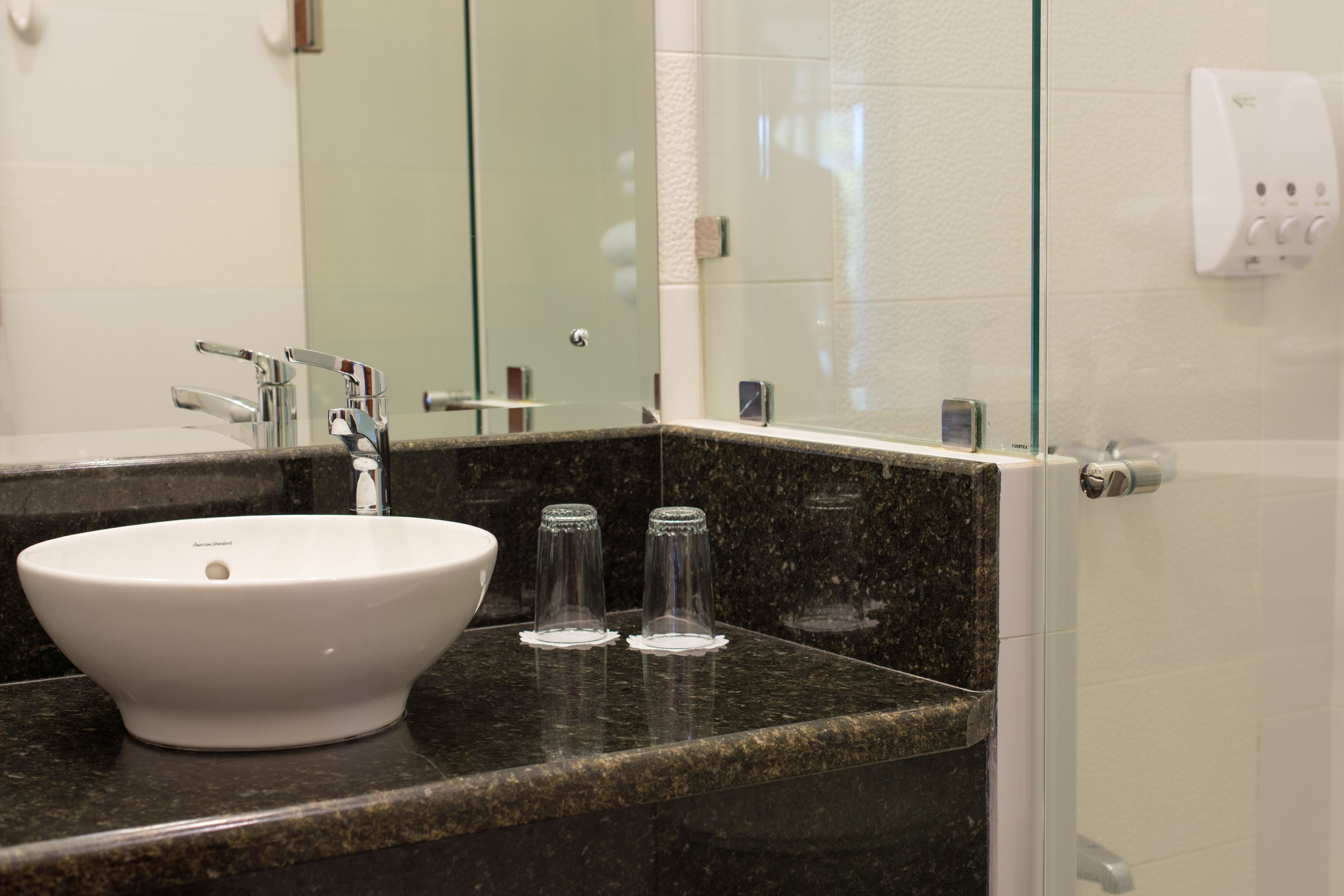 A bathroom with a white sink, a mirror, and a glass shower enclosure.
