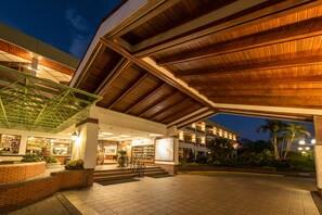 Ein Hotel mit Eingangsbereich, einer überdachten Terrasse, Sitzgelegenheiten im Freien und einem angelegten Garten.
