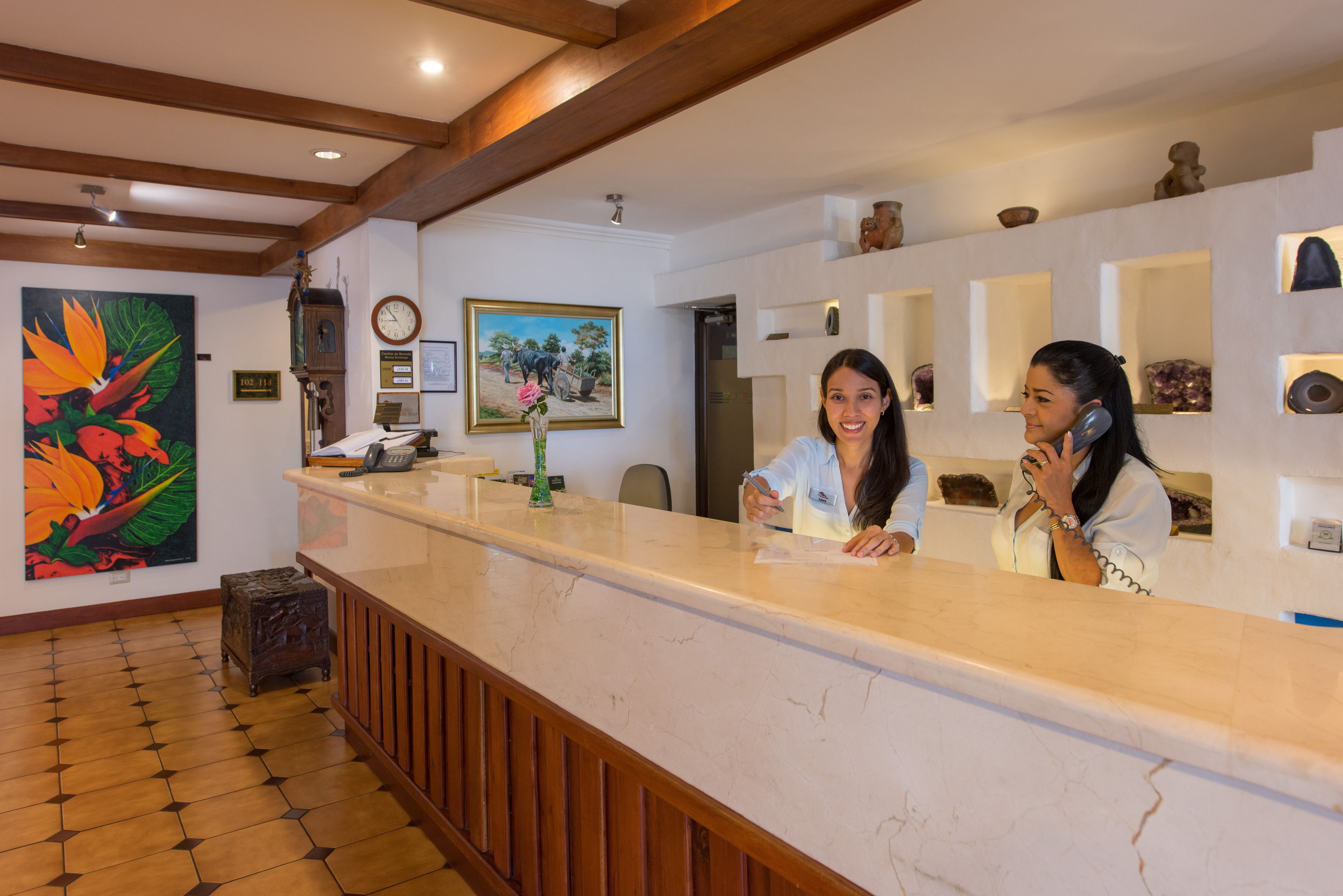 A reception area with a marble counter, wooden accents, and artwork on the walls.