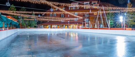 Una pista de hielo cubierta con luces colgantes y un edificio al fondo.