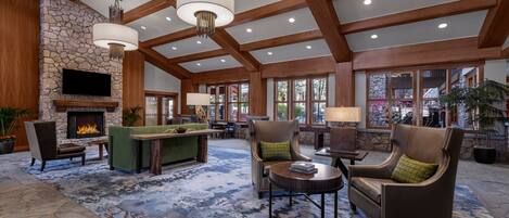 A spacious lobby with a stone fireplace, wooden beams, and comfortable seating areas.