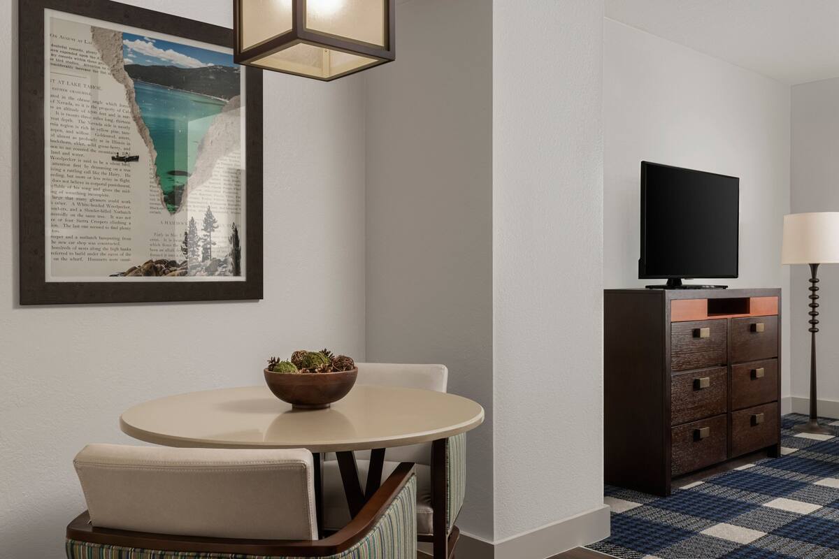 A modern room with a round table, a television, and a framed picture on the wall.