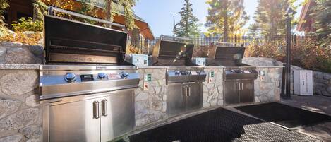 An outdoor kitchen area with stainless steel appliances, stone walls, and a herringbone-patterned floor.