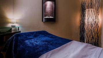 Relax in a stylish room with a comfortable bed, wall-mounted light, and decorative art piece.