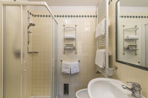 Un bagno con doccia, lavandino e specchio.