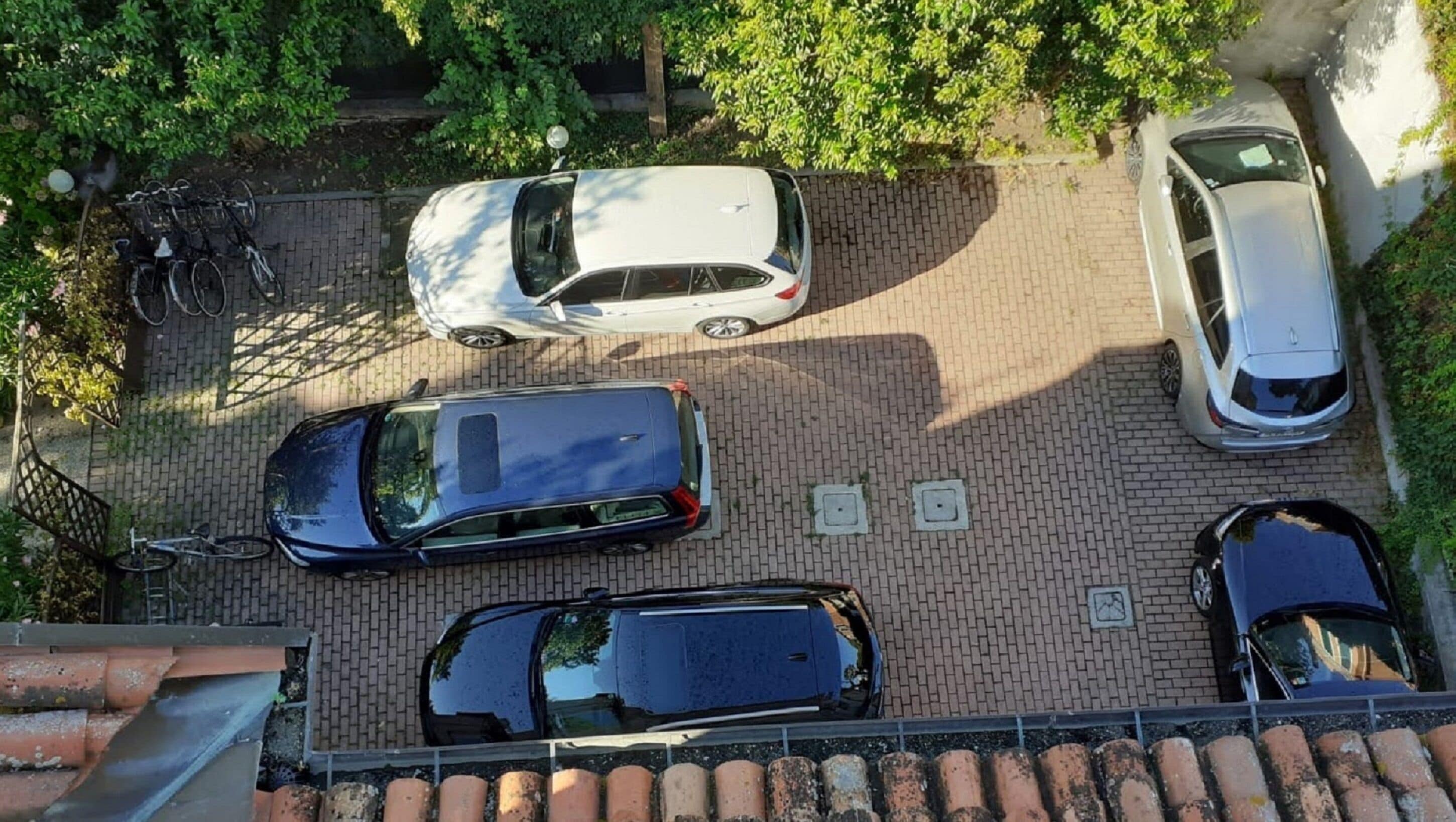 An aerial view of a parking lot with four cars and a bicycle rack.