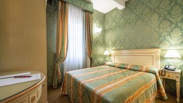 A hotel room with a bed, a desk, and a nightstand.