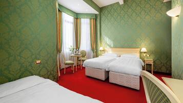 A hotel room with two beds, a desk, a chair, and a small table.