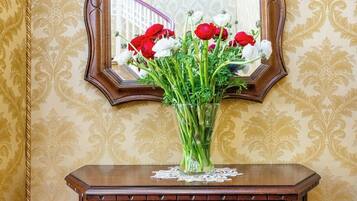 A mirror with a floral pattern, a vase with red and white flowers, and a wooden cabinet with drawers.