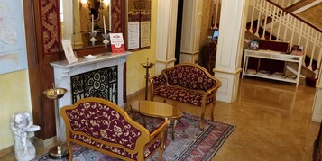 Una hall con camino, una poltrona, un tavolino e una scala.