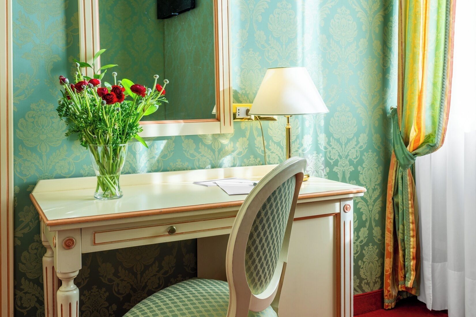 A room with a desk, a mirror, a lamp, and a chair.