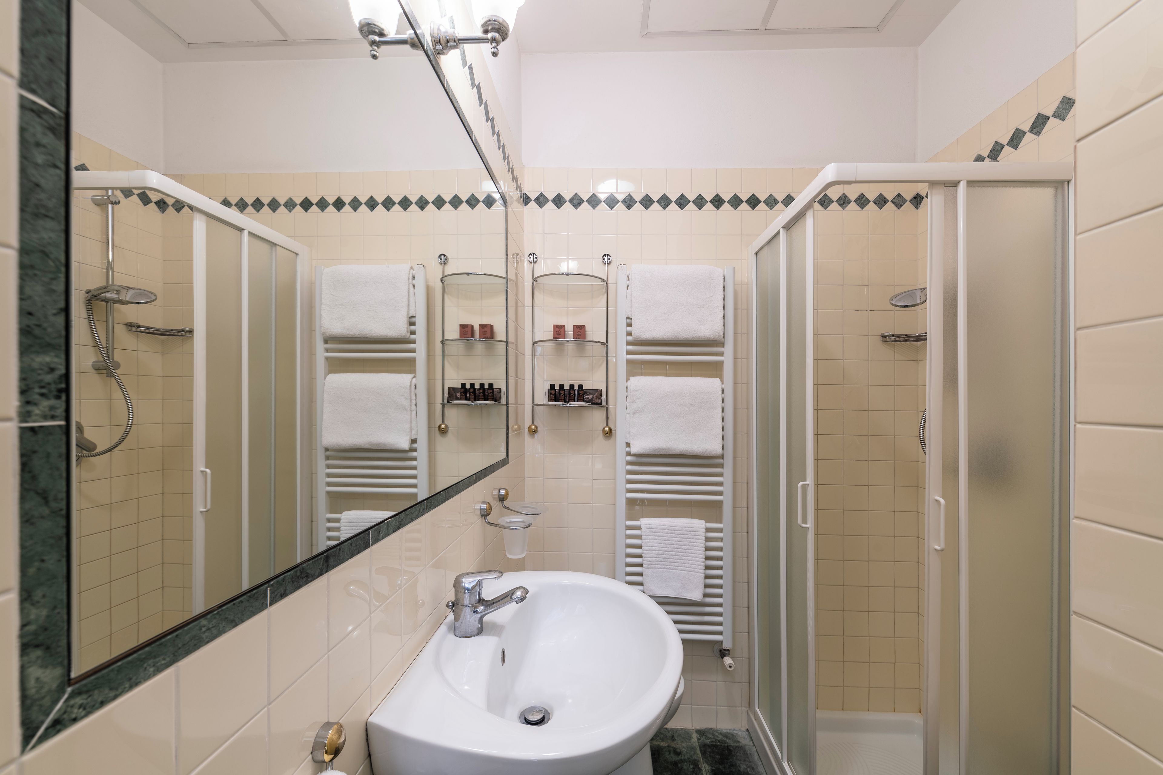 A bathroom with a white sink, a glass shower enclosure, and a mirror.