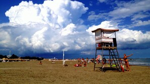 Uma praia com uma torre salva-vidas, areia dourada e céu claro com nuvens.