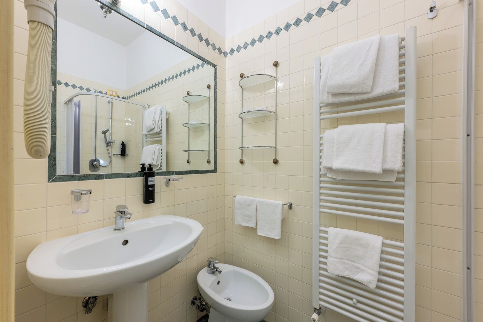 Ein Badezimmer mit Waschbecken, Bidet, Spiegel, Handtuchhalter und Handtuchwärmer.