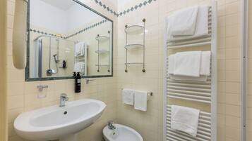Ein Badezimmer mit Waschbecken, Bidet, Spiegel, Handtuchhalter und Handtuchwärmer.