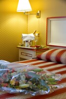 Camera d'albergo con un letto, un comodino, una lampada e una parete con carta da parati decorata.