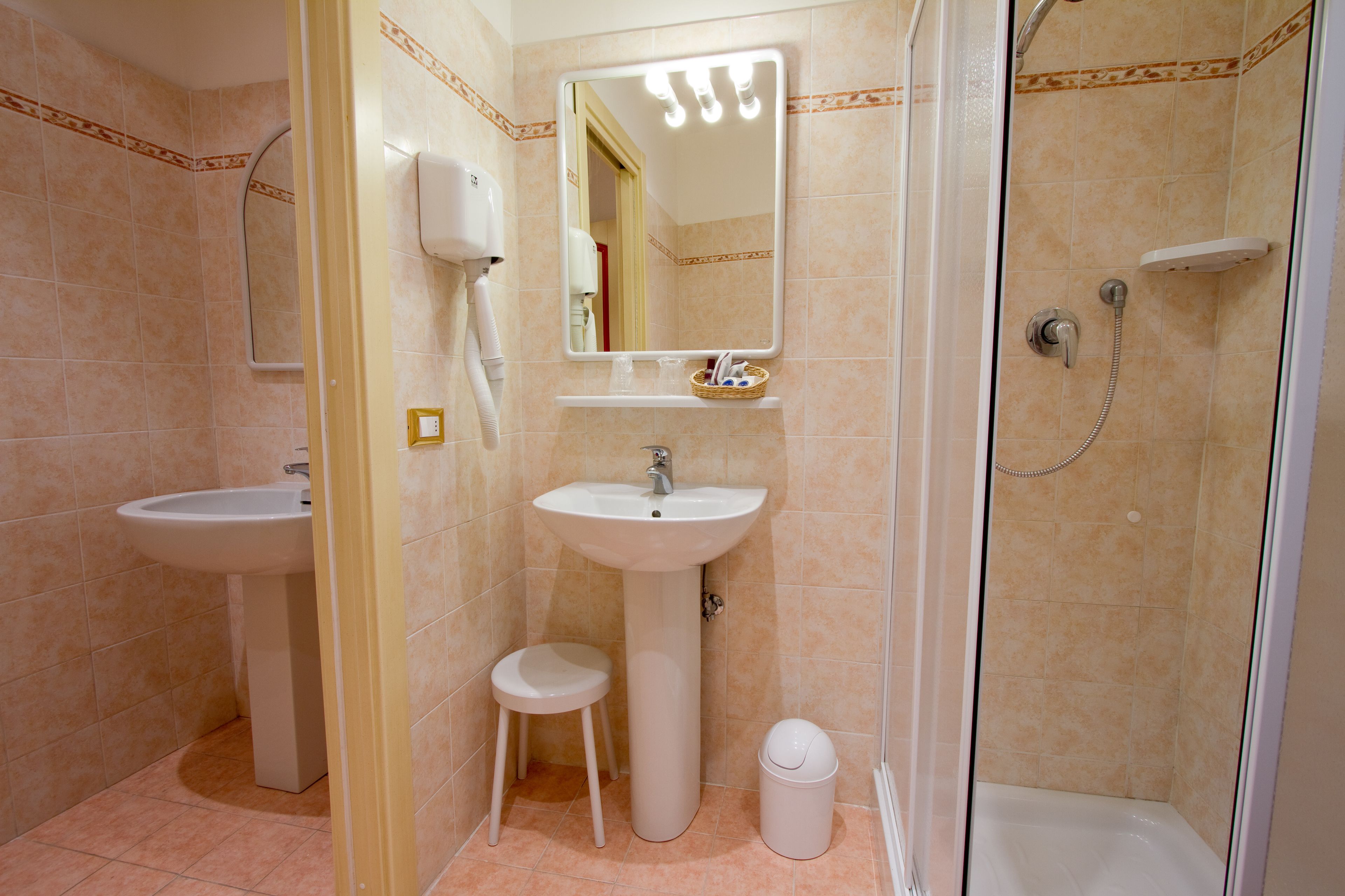 A bathroom with a sink, mirror, and shower.