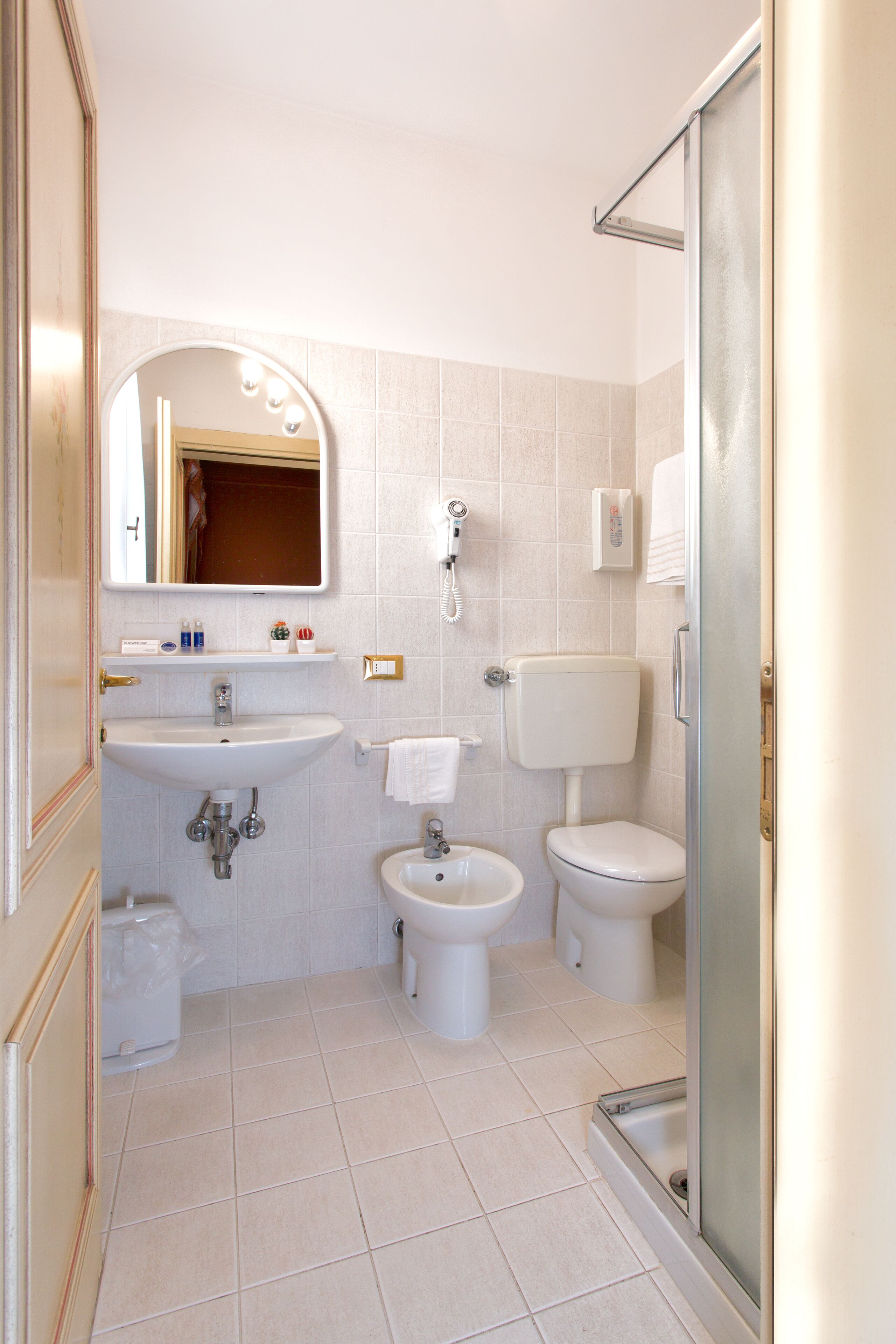 A bathroom with a sink, bidet, toilet, and a glass shower enclosure.