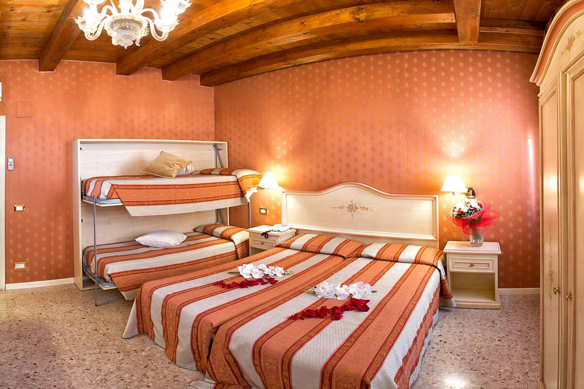 Habitación de hotel con dos camas, techo de madera y pared con estampado rosa.