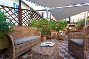 A covered outdoor seating area with wicker furniture and potted plants.