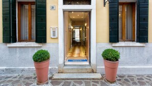 A hotel entrance with a checkered floor, green shutters, and potted plants. -  Hotel Conterie (Venice)